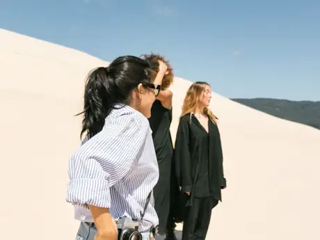Trois amies en haut d'une dune, à contre-jour.